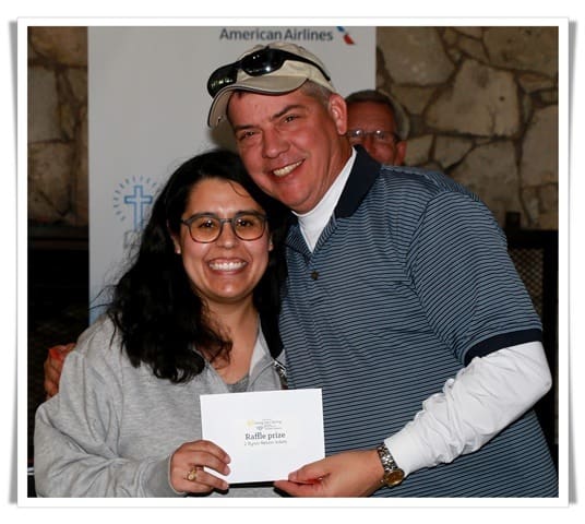A man and woman smiling while holding a check.