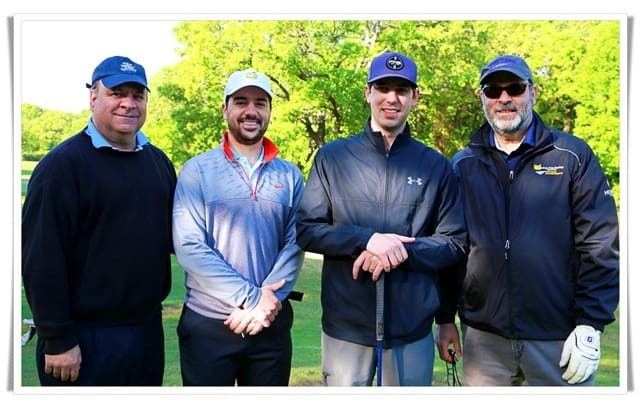 Four men posing for a photo on a golf course.