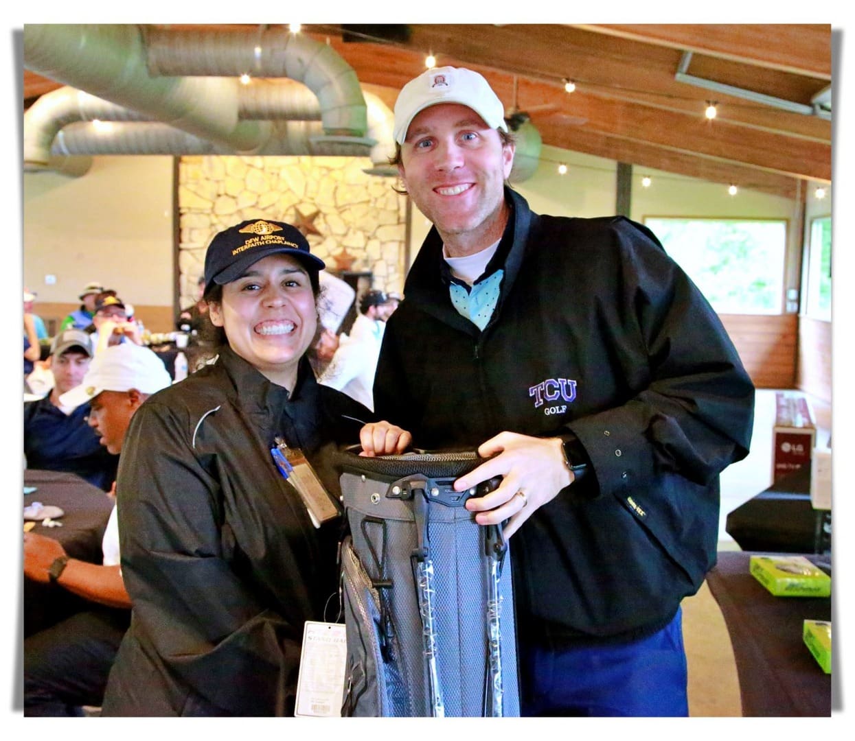 A man and woman posing with a golf bag.