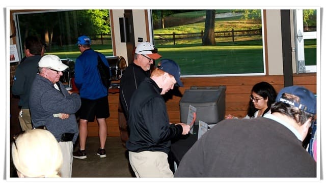 A group of people standing around a table at a golf tournament.