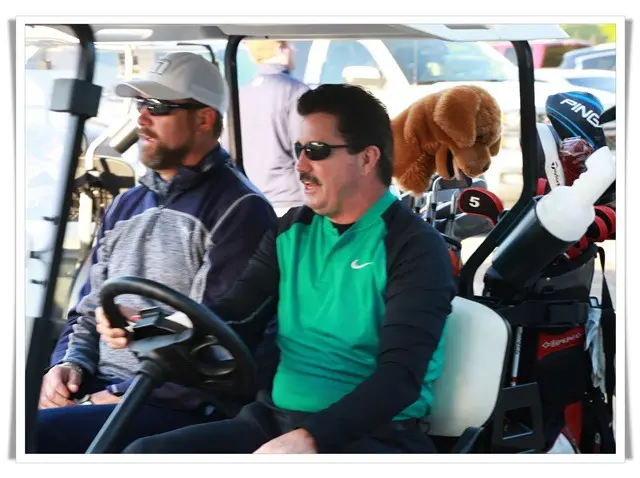 Two men sitting in a golf cart with a teddy bear.