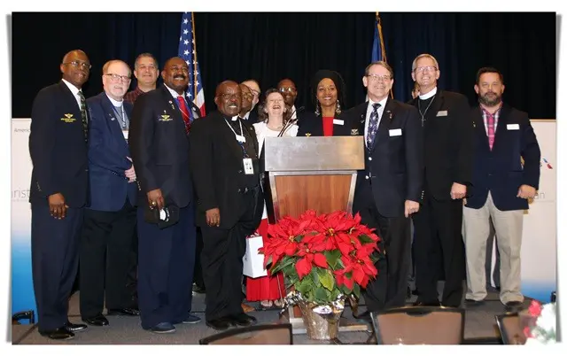 group photo of men and women with a podium and poinsettias