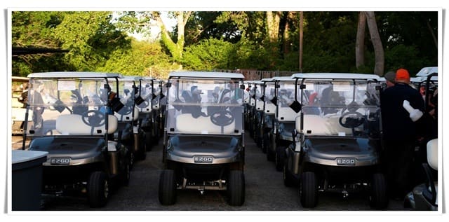 A group of golf carts lined up in a parking lot.
