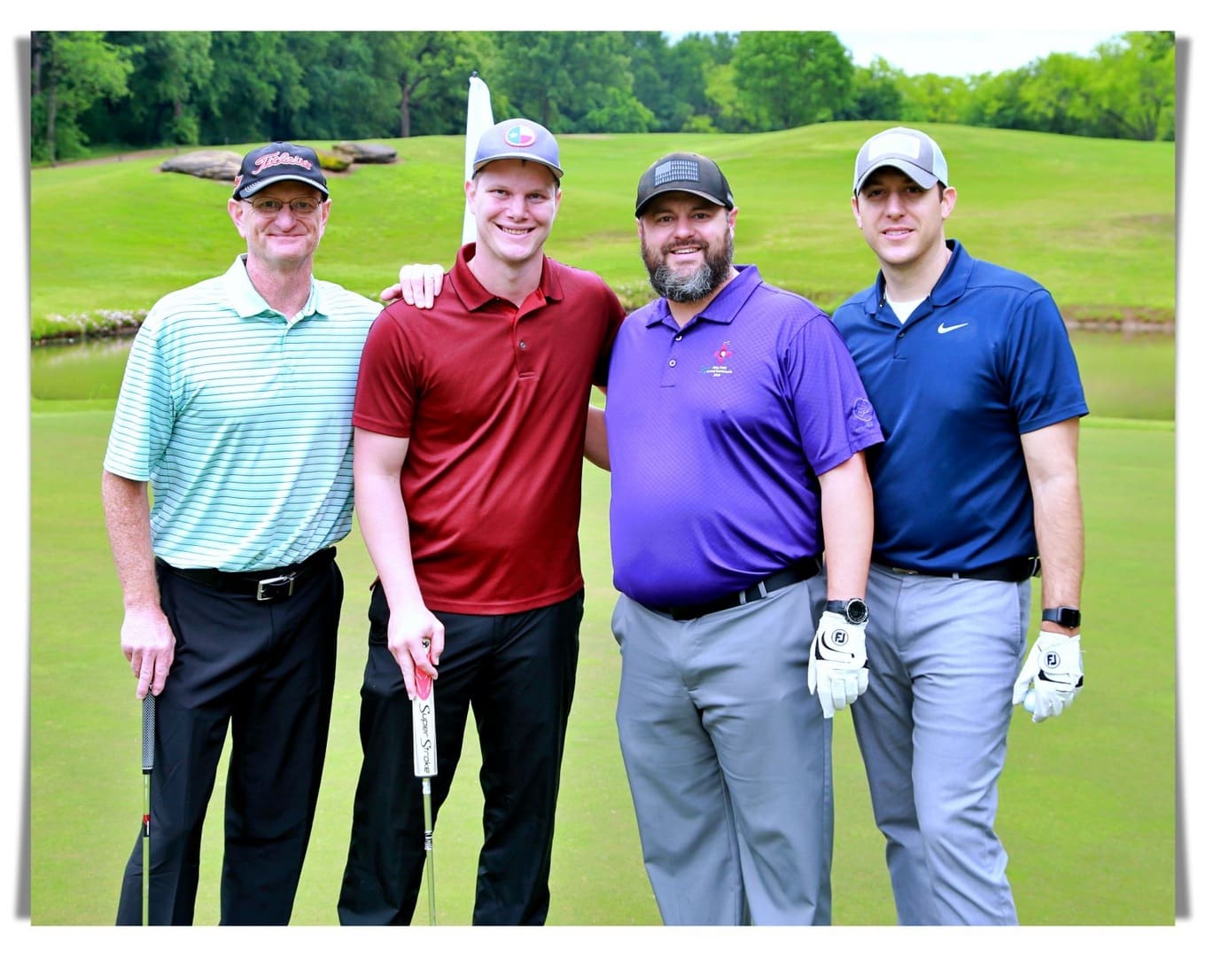 Four men posing for a photo on a golf course.