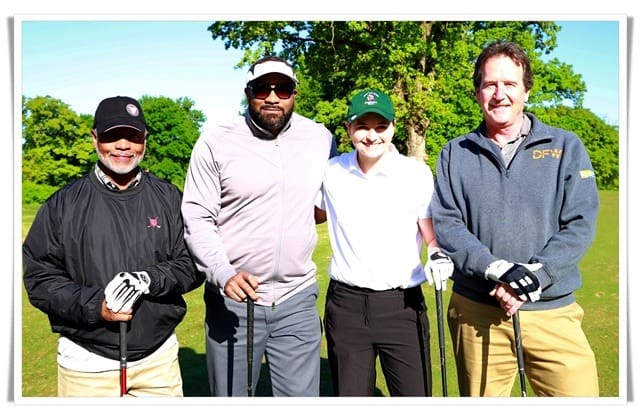Four men posing for a picture on a golf course.