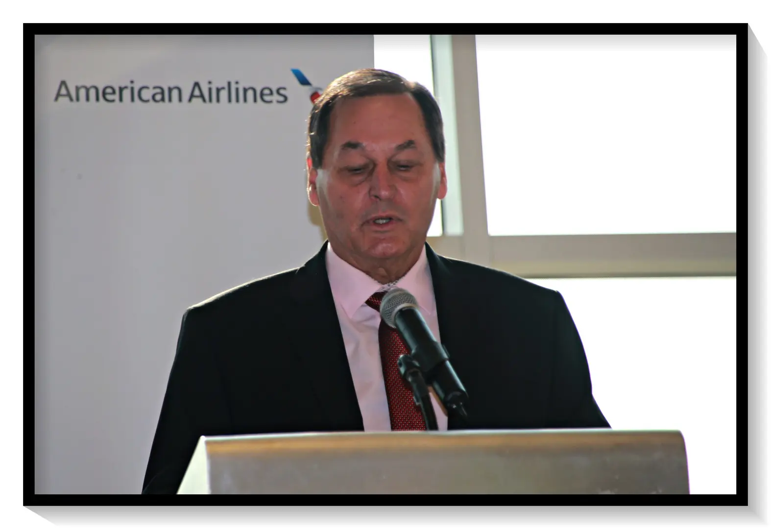 A man standing at a podium in front of an american airlines sign.