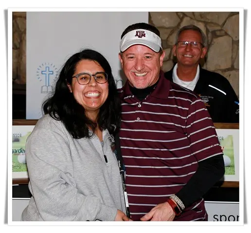A man and woman posing for a photo at a golf tournament.