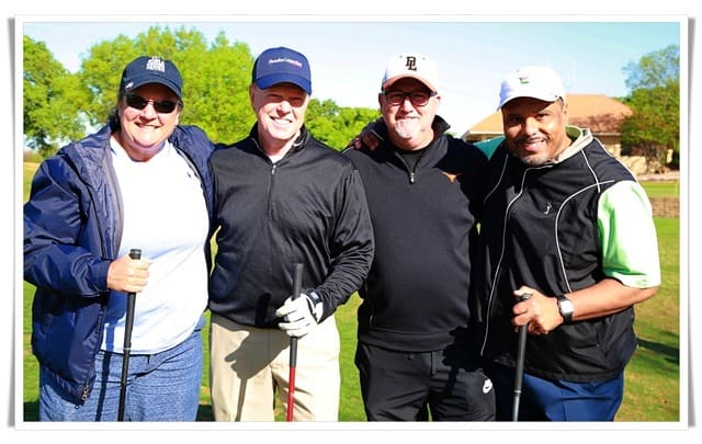 Four men posing for a photo at a golf course.