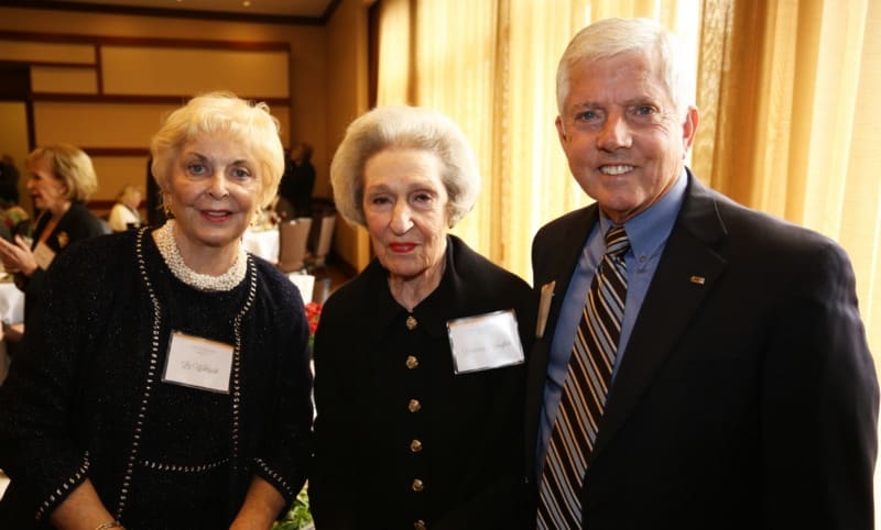 Three older people posing for a photo at an event.