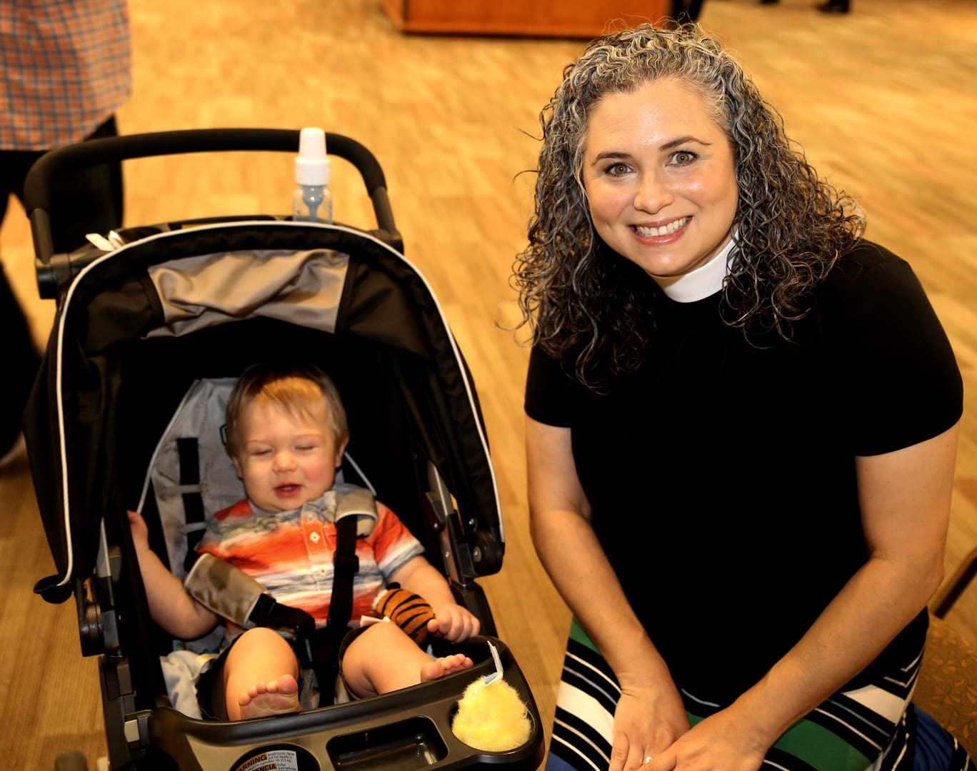 A woman poses with a baby in a stroller.