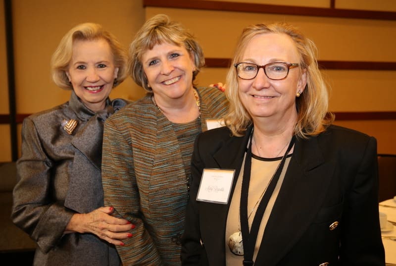 Three women standing next to each other at an event.