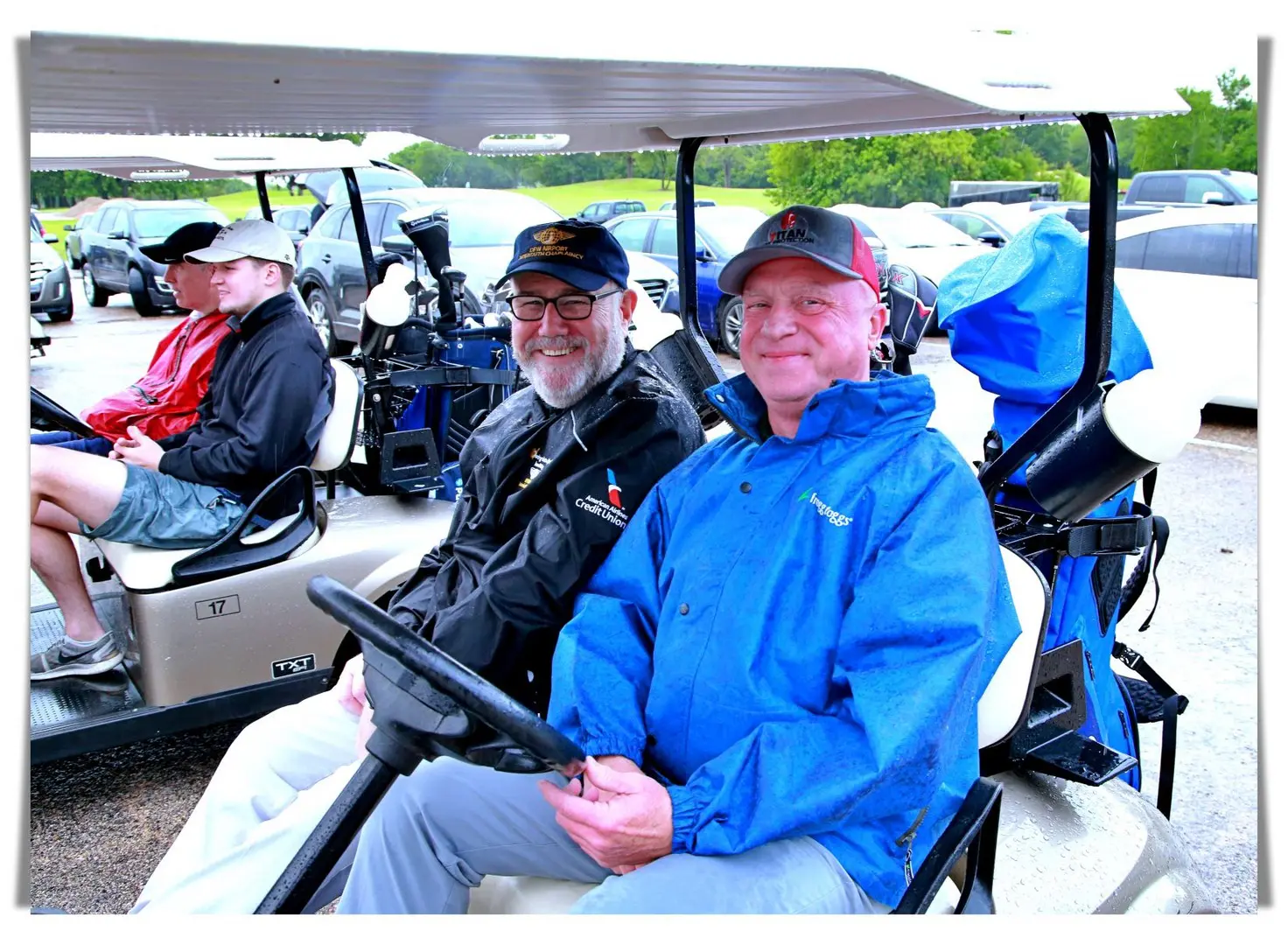 Two men sitting in a golf cart on a rainy day.