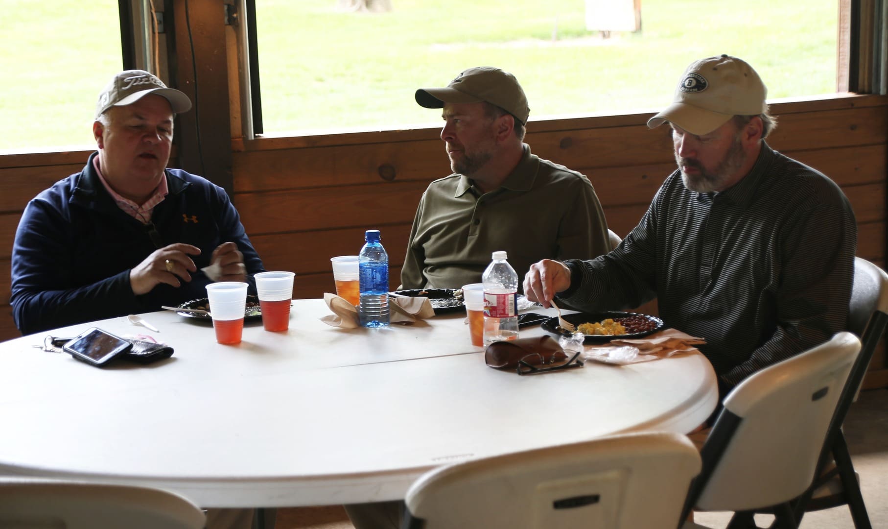 Three men sitting at a table eating food.