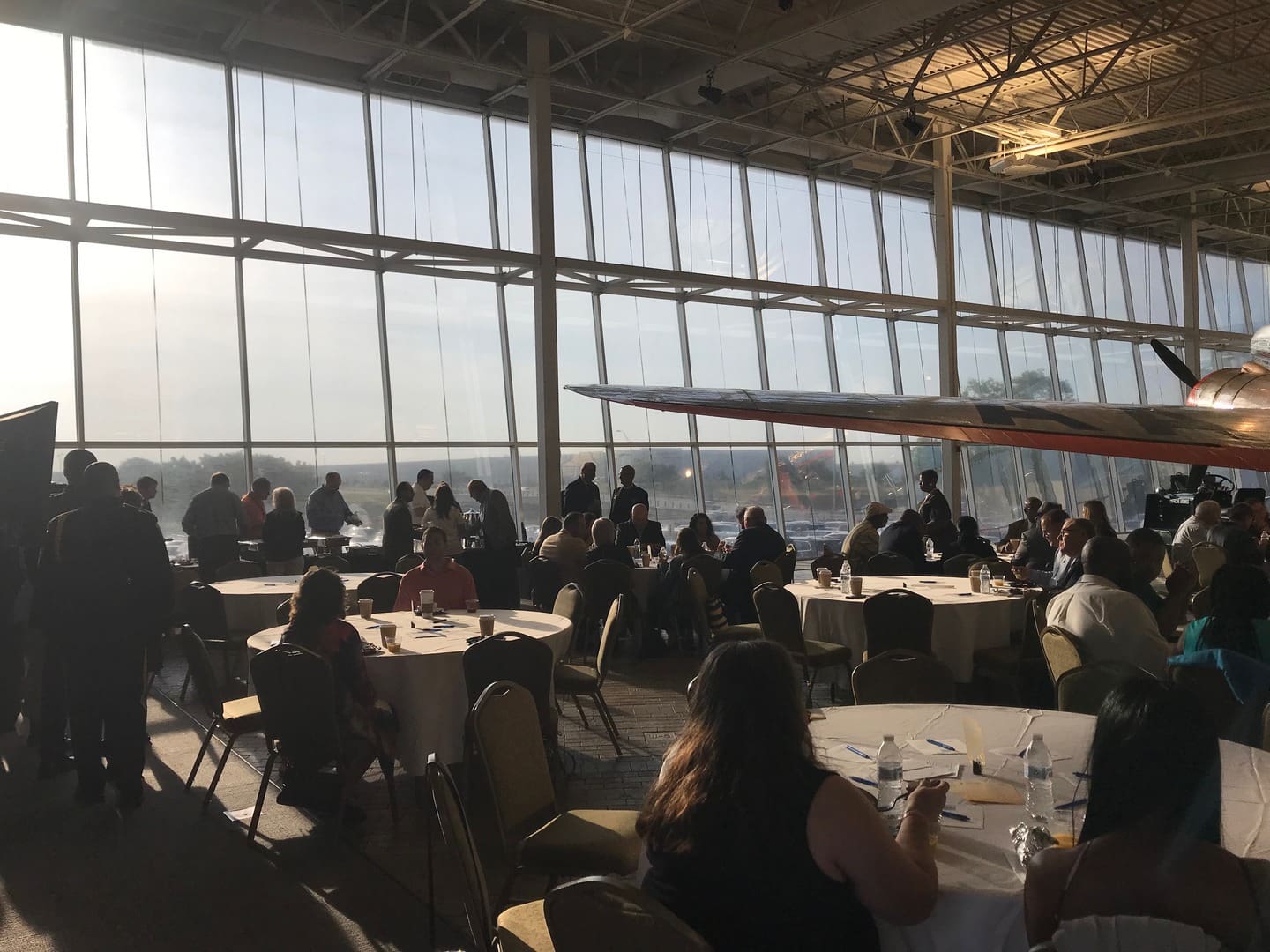 sunlit view of plane and blue sky on windows with people eating