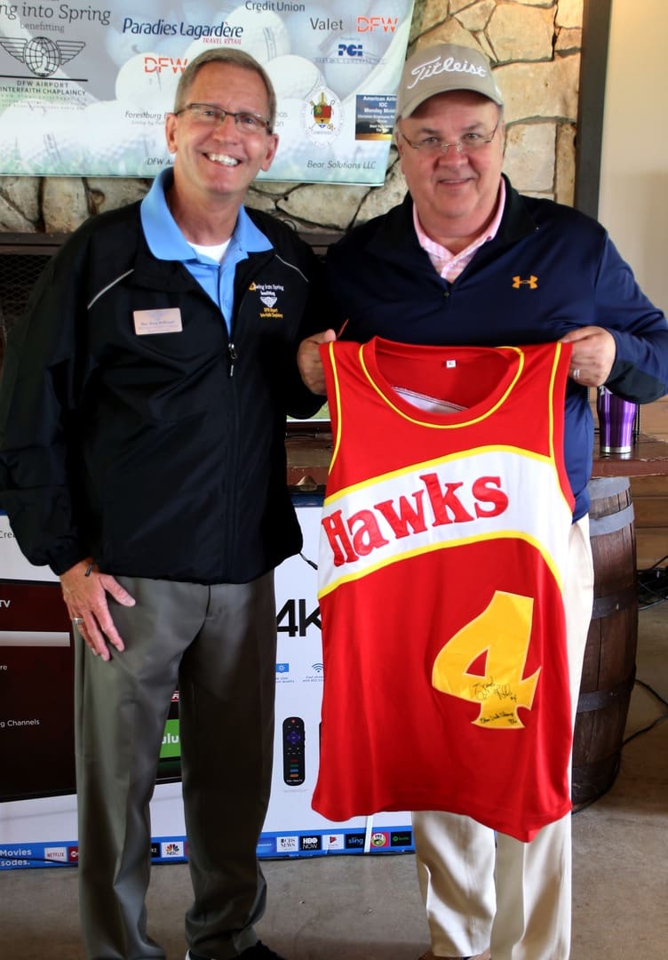 Two men posing with a basketball jersey.
