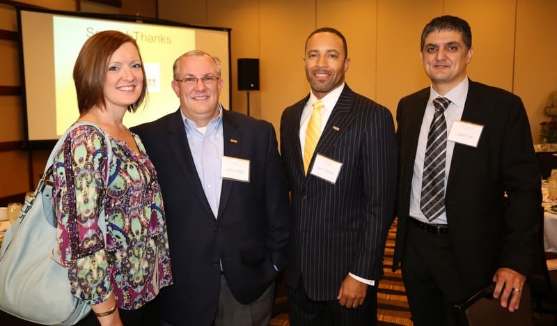 Four people posing for a picture at a business event.