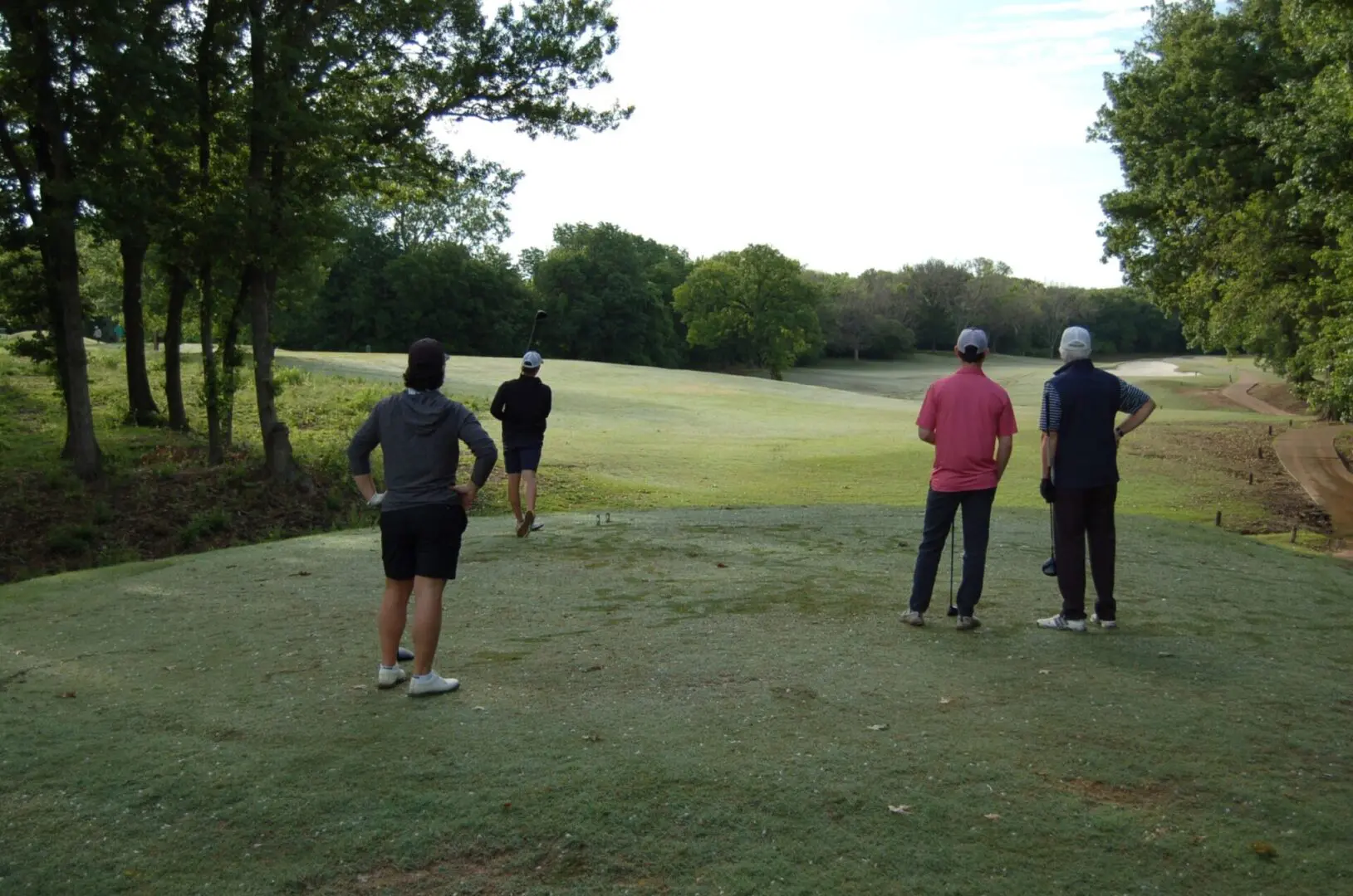 A group of people standing on a golf course.