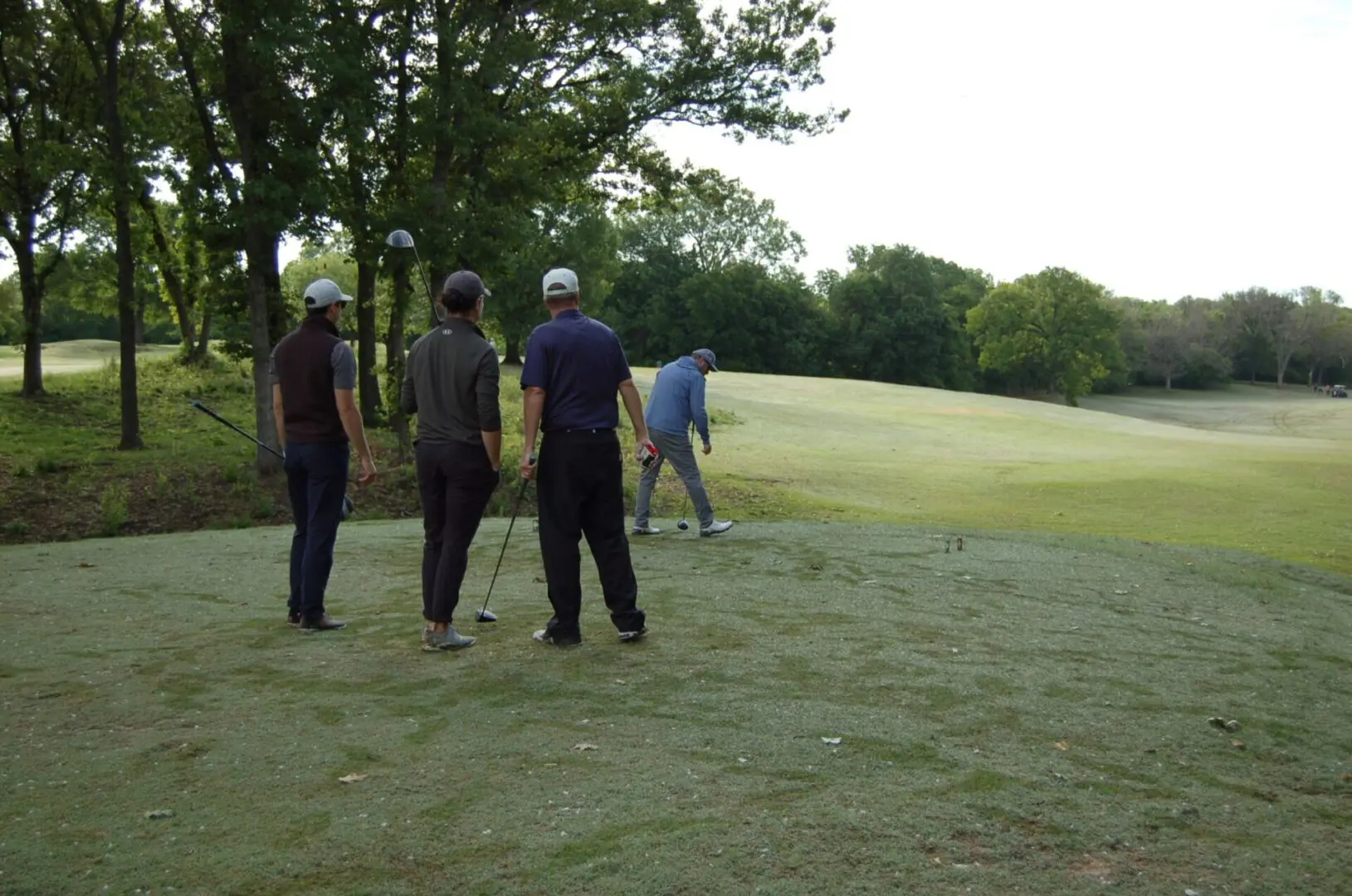 A group of people standing on a golf course.
