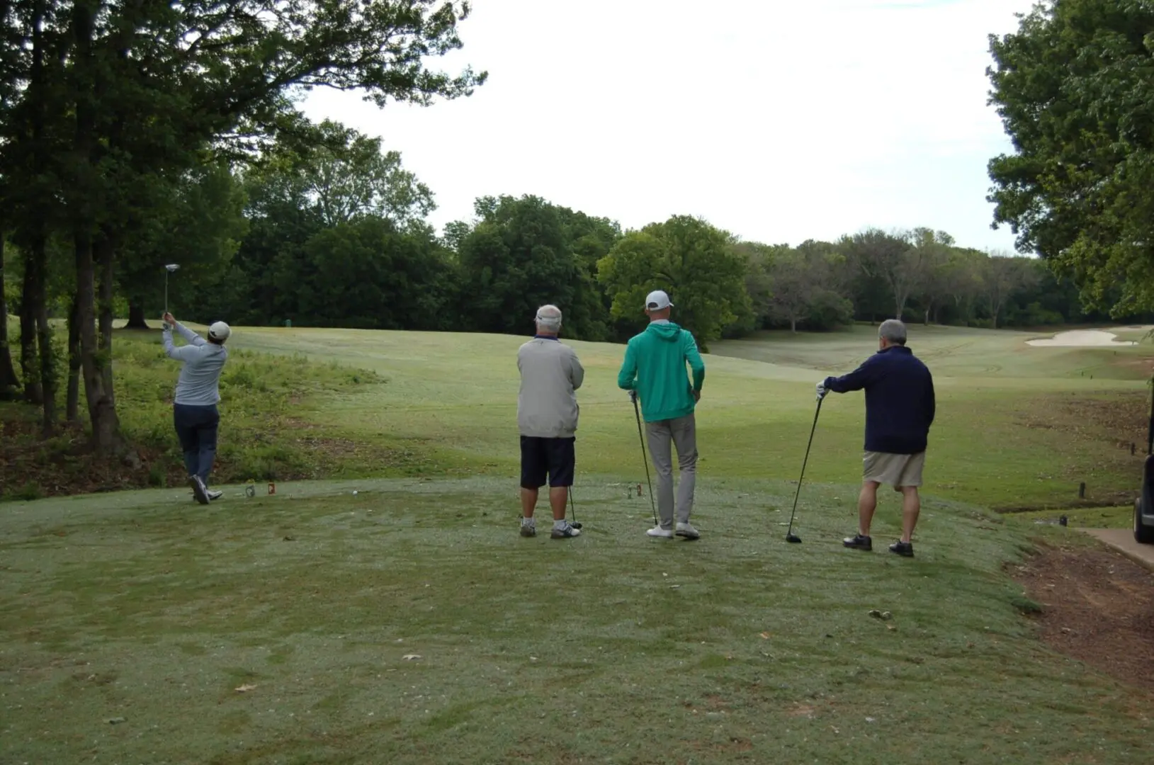 A group of people playing golf on a golf course.