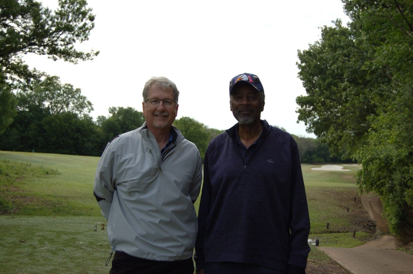 Two men standing next to each other on a golf course.
