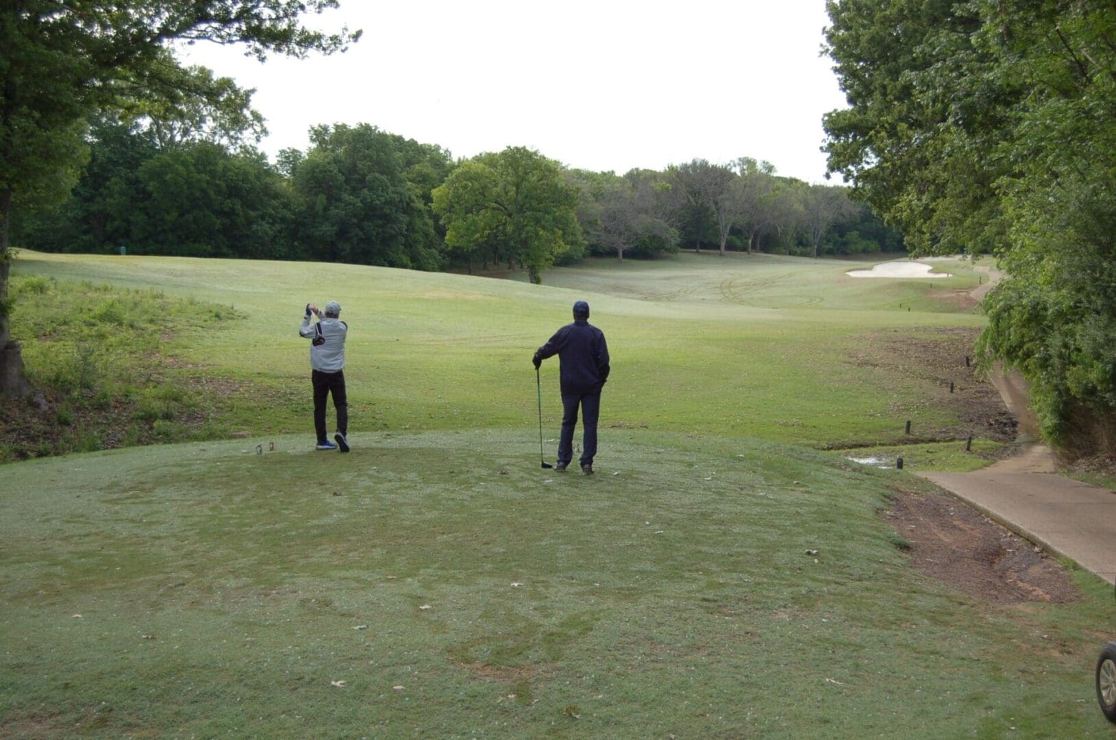 Two people playing golf on a golf course.