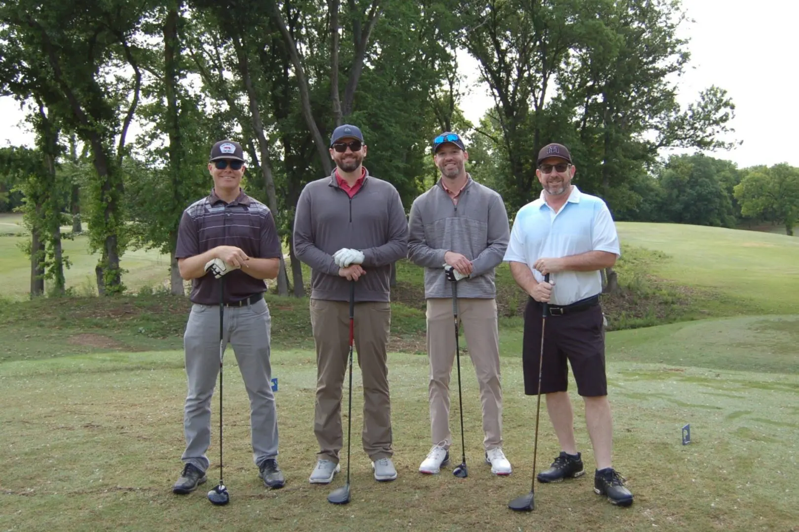 Four men posing for a picture on a golf course.