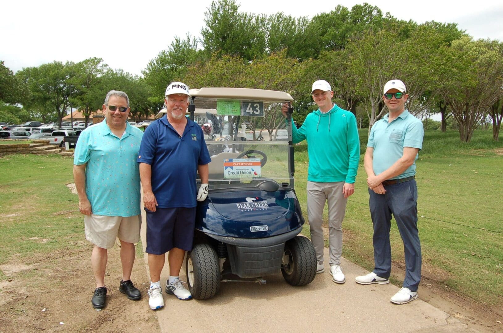 Four men standing next to a golf cart.