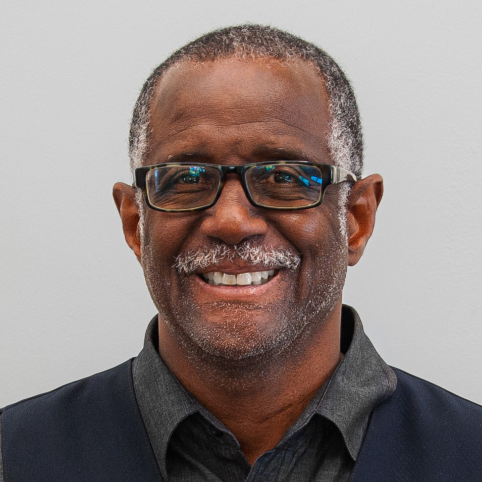 Smiling man with glasses and mustache.