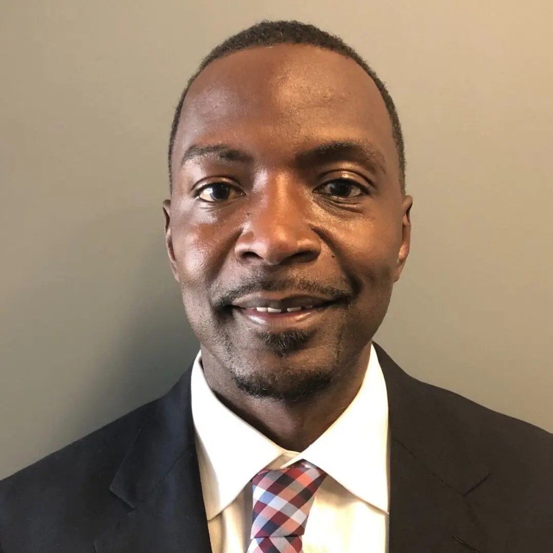 Man in suit with a tie smiling.