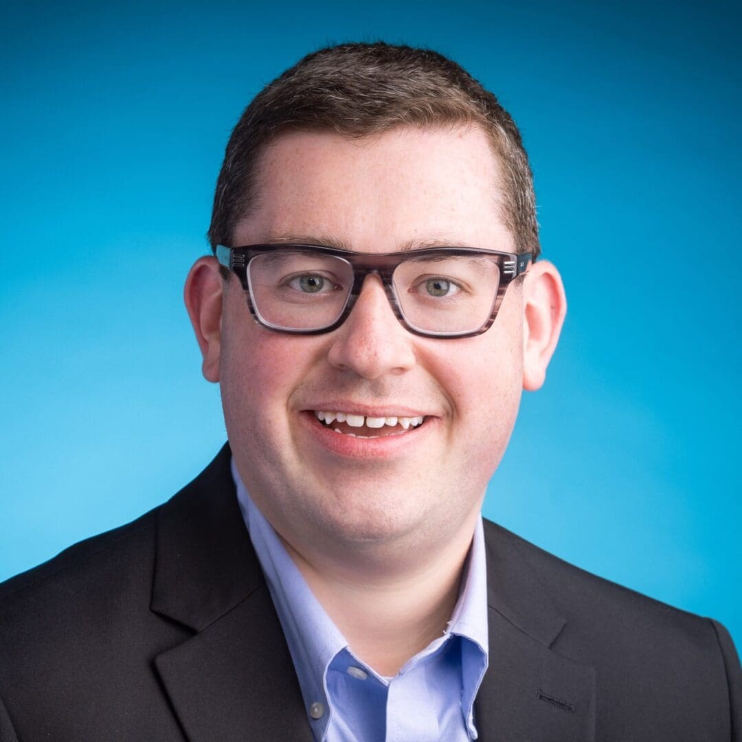 Smiling man wearing glasses and a suit.